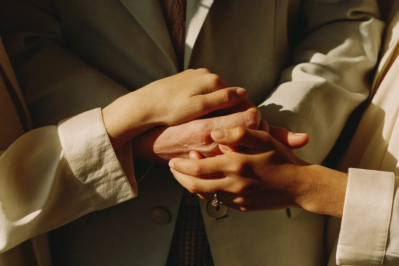 Two pairs of hands gently clasped in warm light